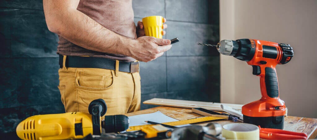 Jak vybrat aku nářadí man using smart phone holding cup coffee