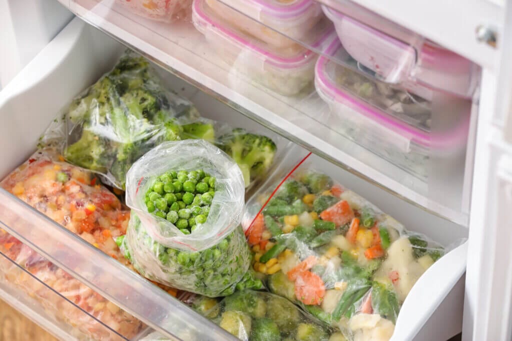 Jak správně uchovat potraviny v mrazáku plastic bags with frozen green peas different vegetables refrigerator