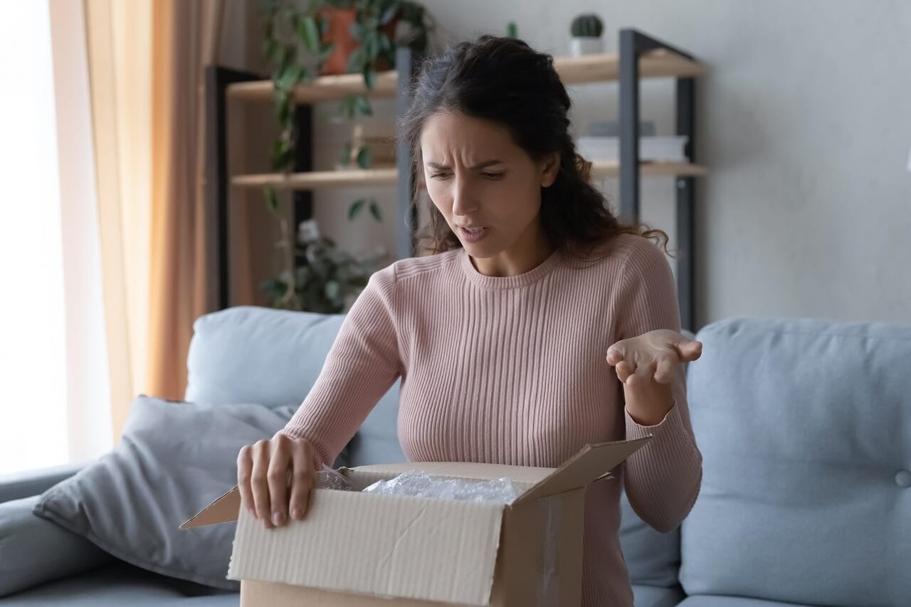 angry confused woman unpacking parcel wrong broken online store order sitting couch home dissatisfied female looking cardboard box bad delivery service displeased by post shipping