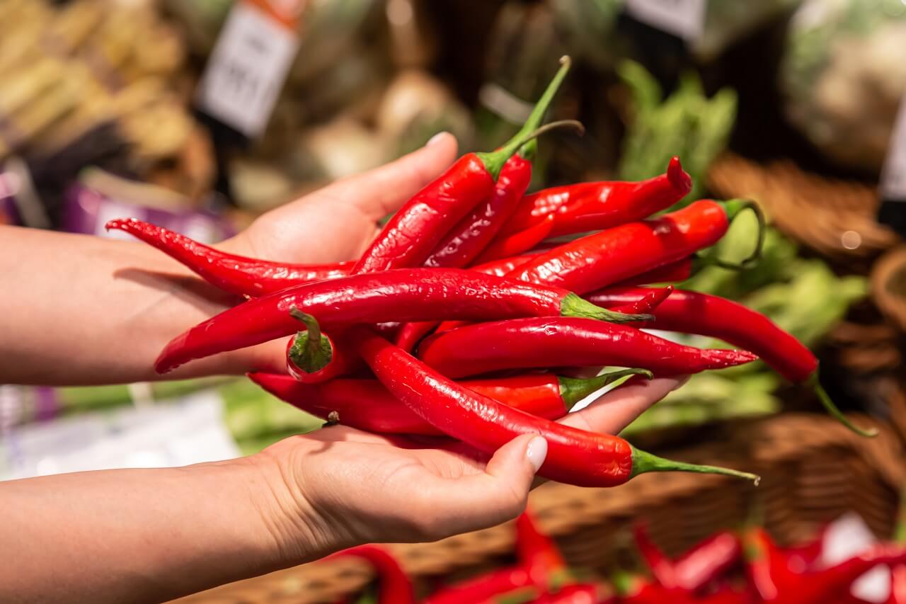woman holds red chilli store market close up